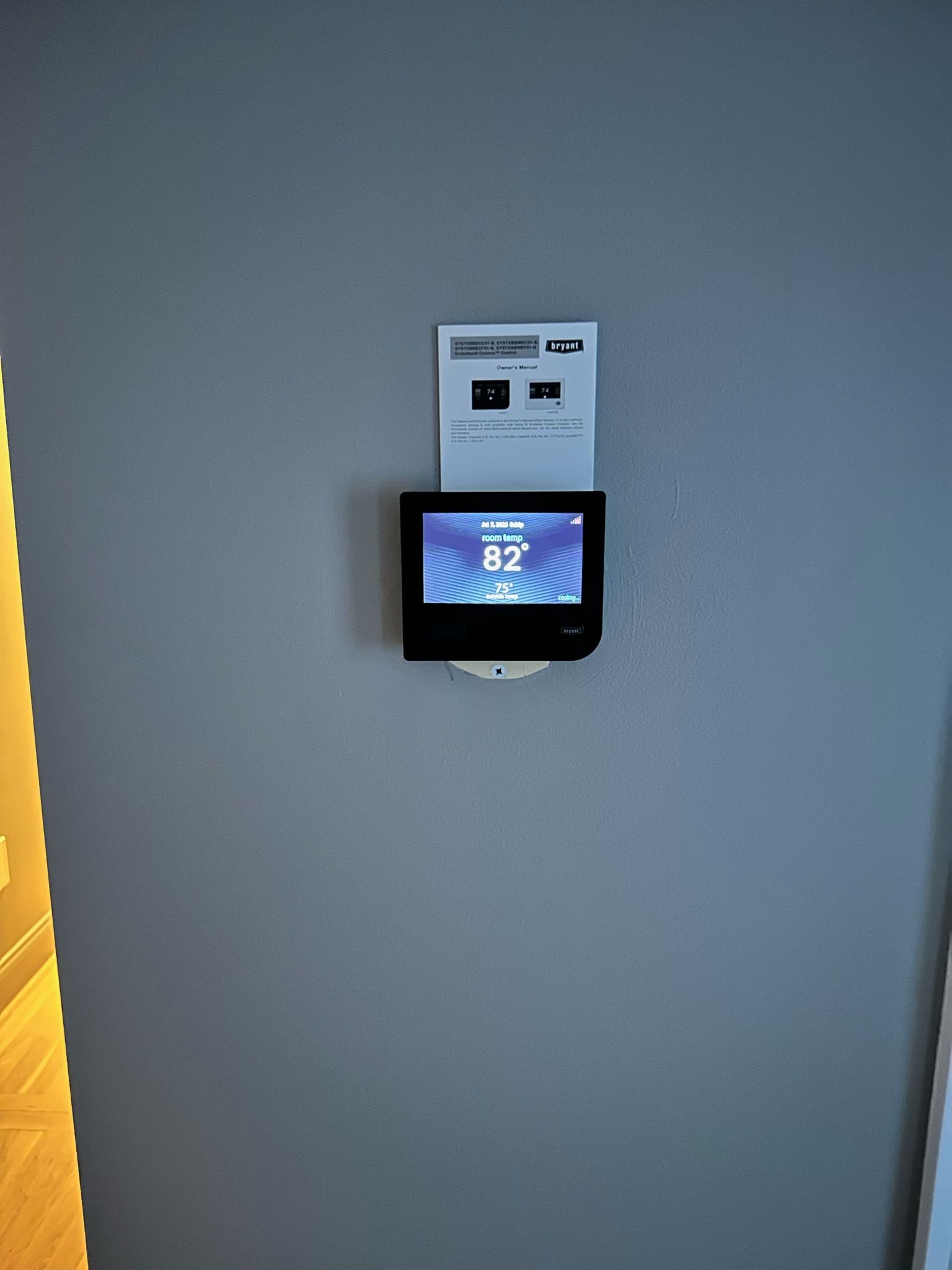A wall-mounted thermostat with a digital display showing the set temperature.