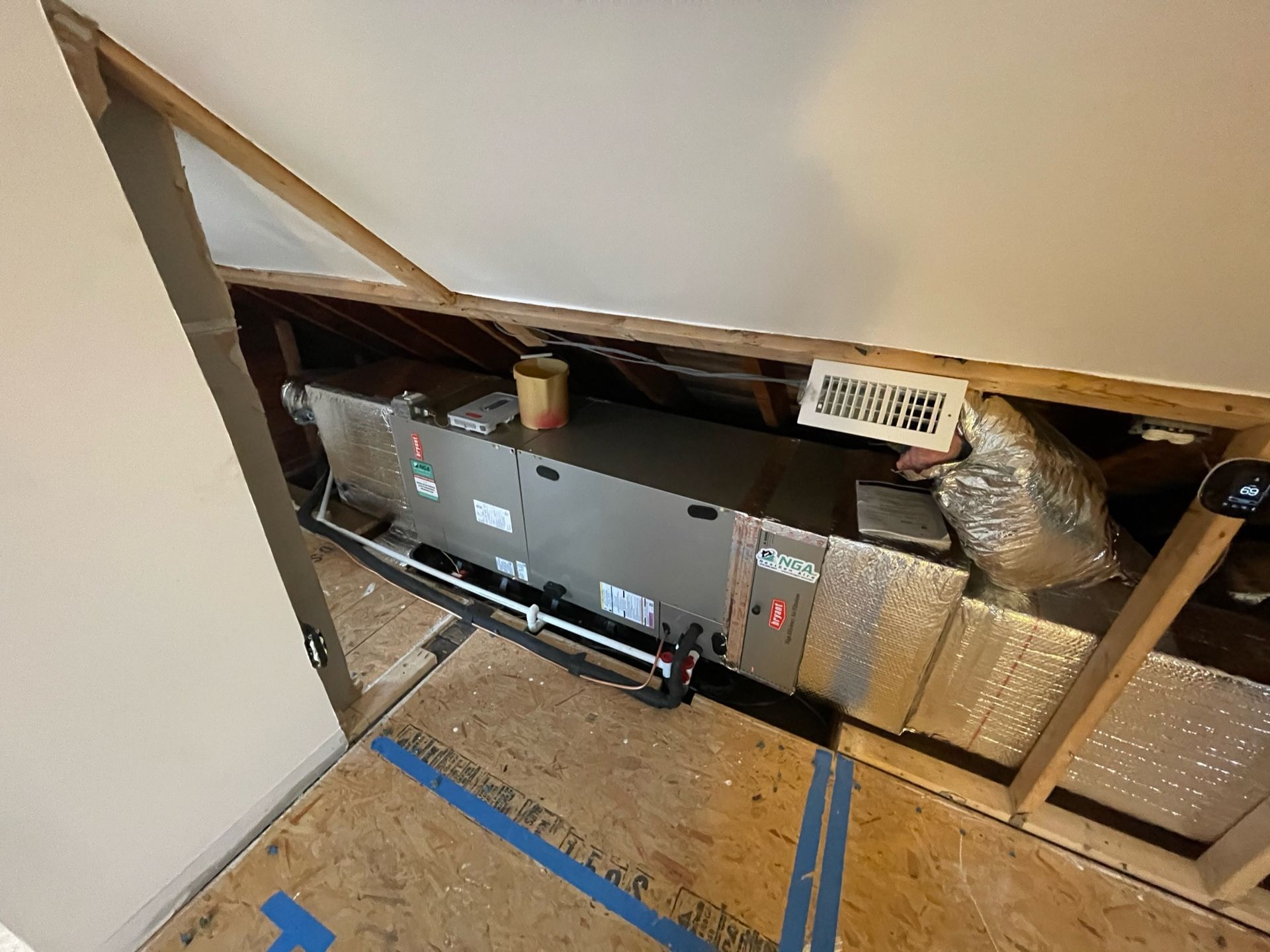 HVAC system in attic with ductwork, insulation, and ventilation. Wooden framing and flooring visible.