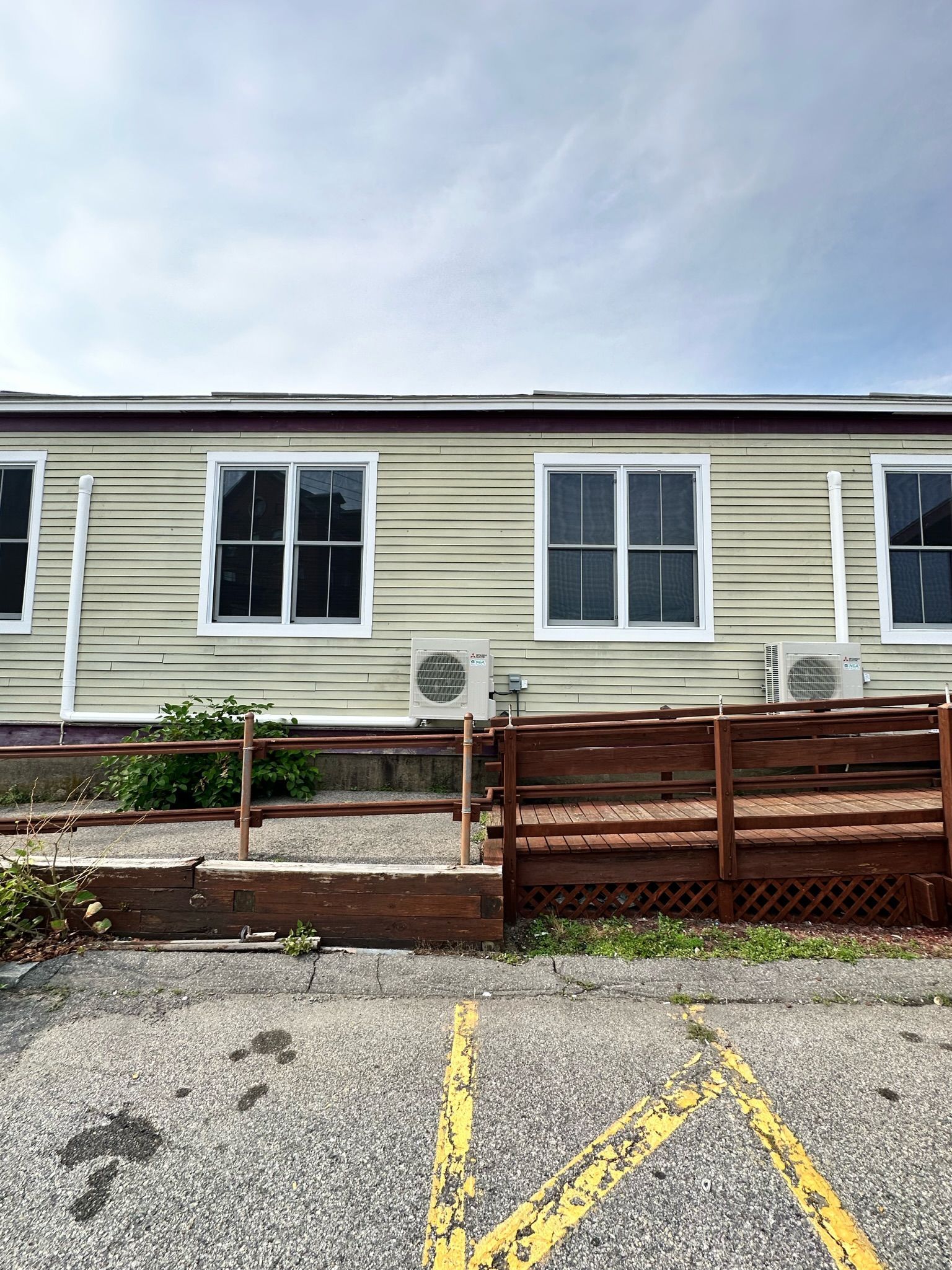 Exterior of a building with windows, a small ramp, and a gravel parking area.