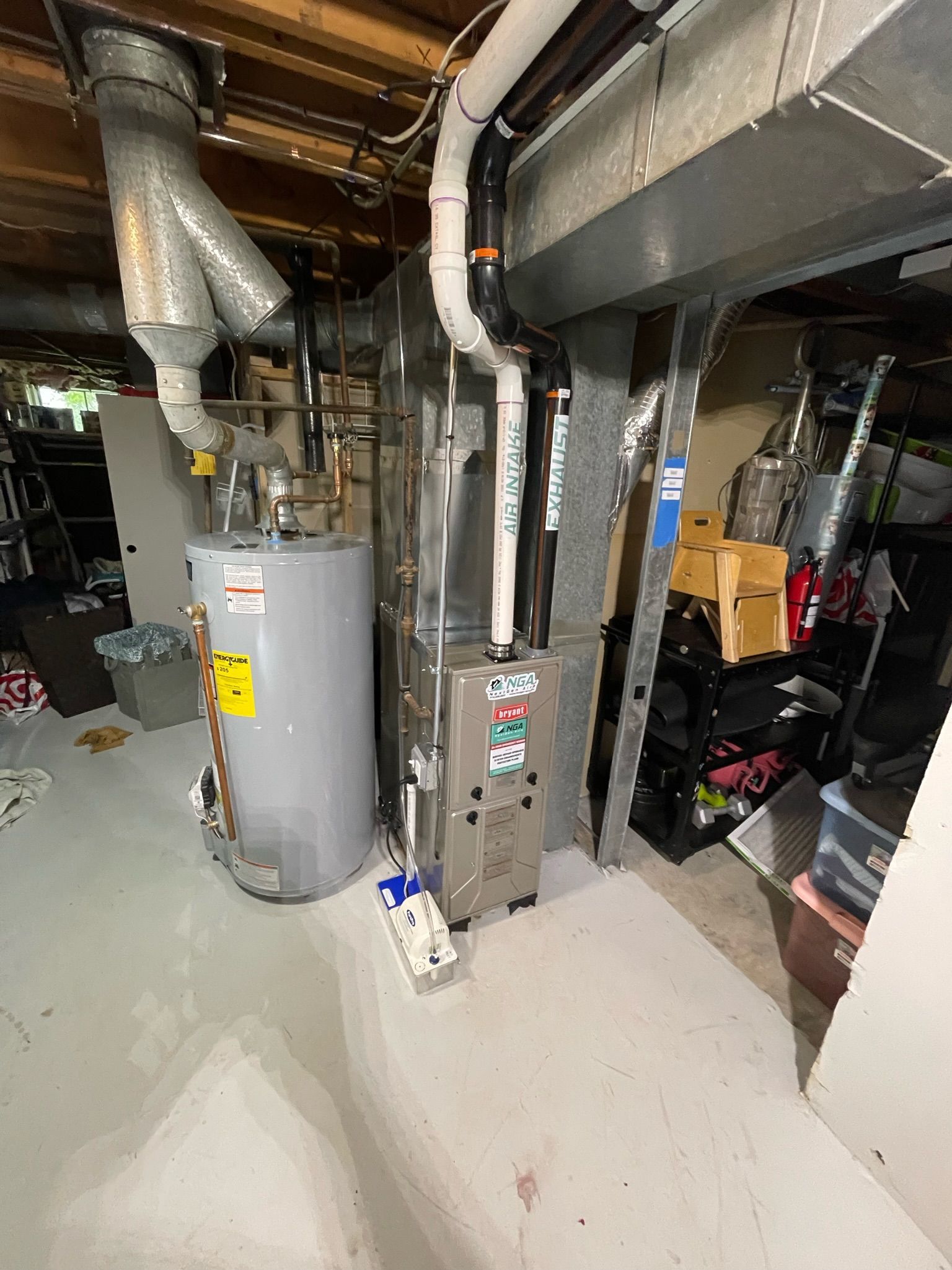 Basement with water heater, furnace, ducts, and miscellaneous clutter. White and gray tones.
