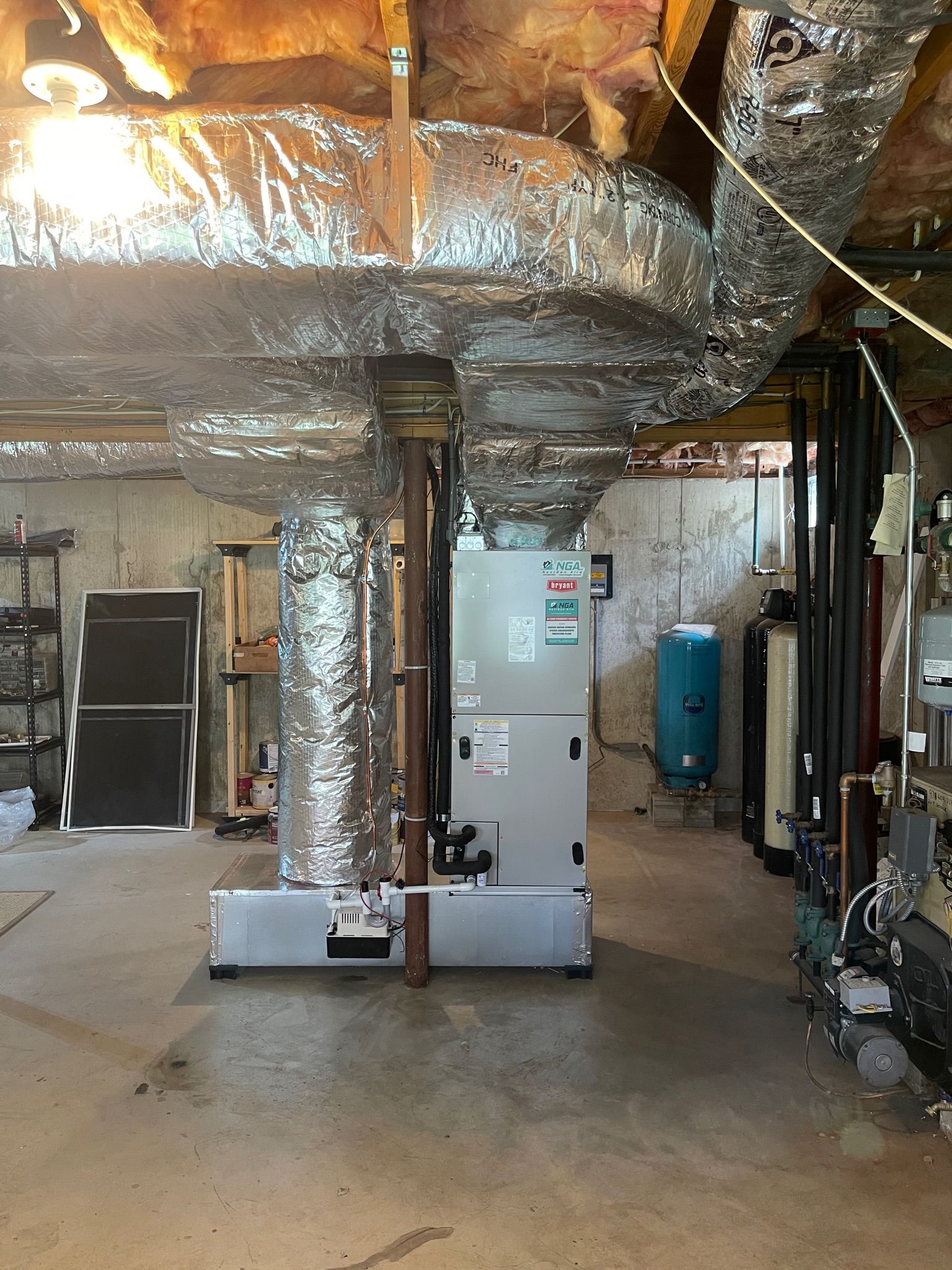 HVAC system and ductwork in a basement. Silver ductwork, white furnace, concrete floor.