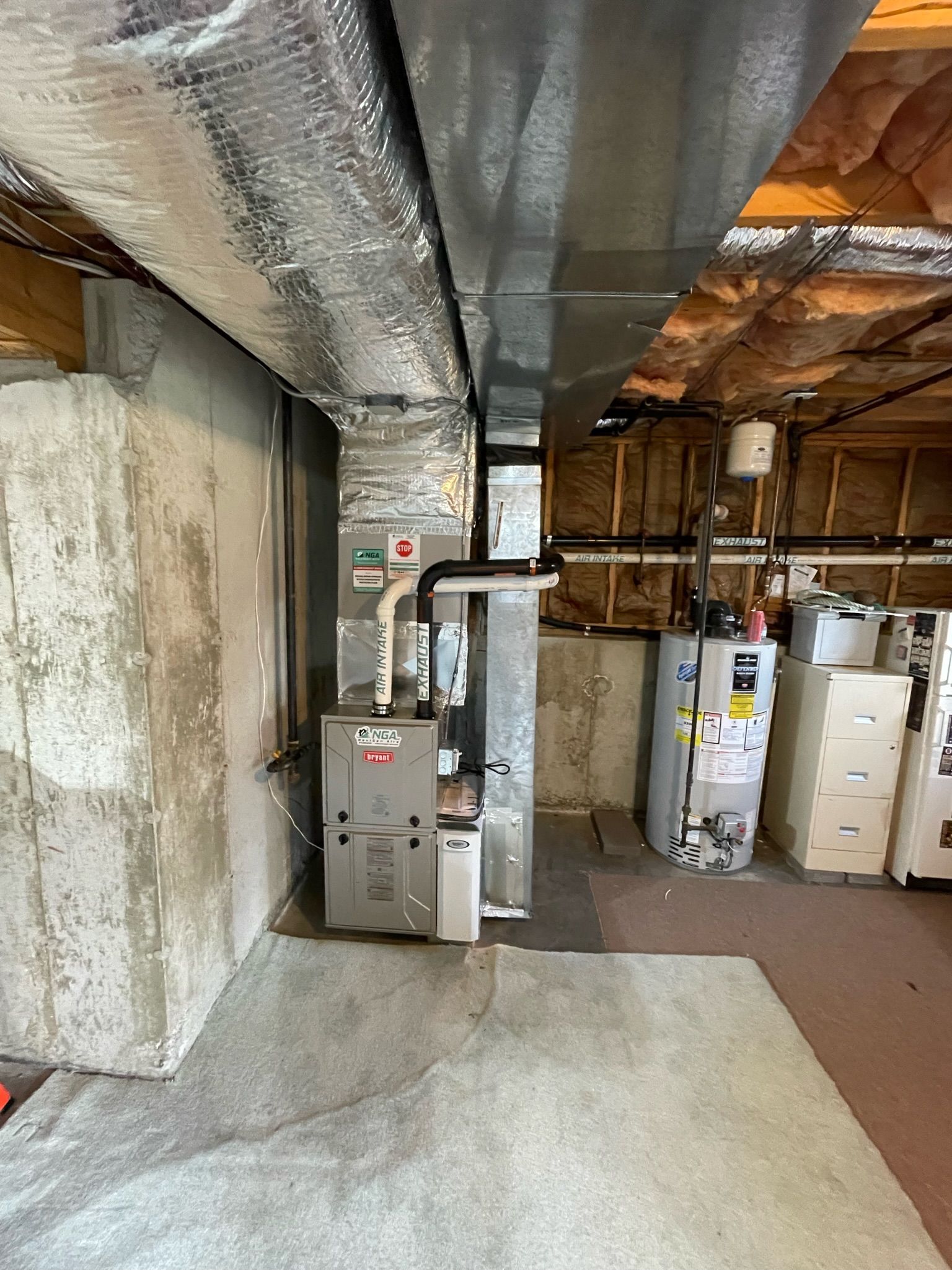 Basement with HVAC system, water heater, ductwork, concrete walls and floor.