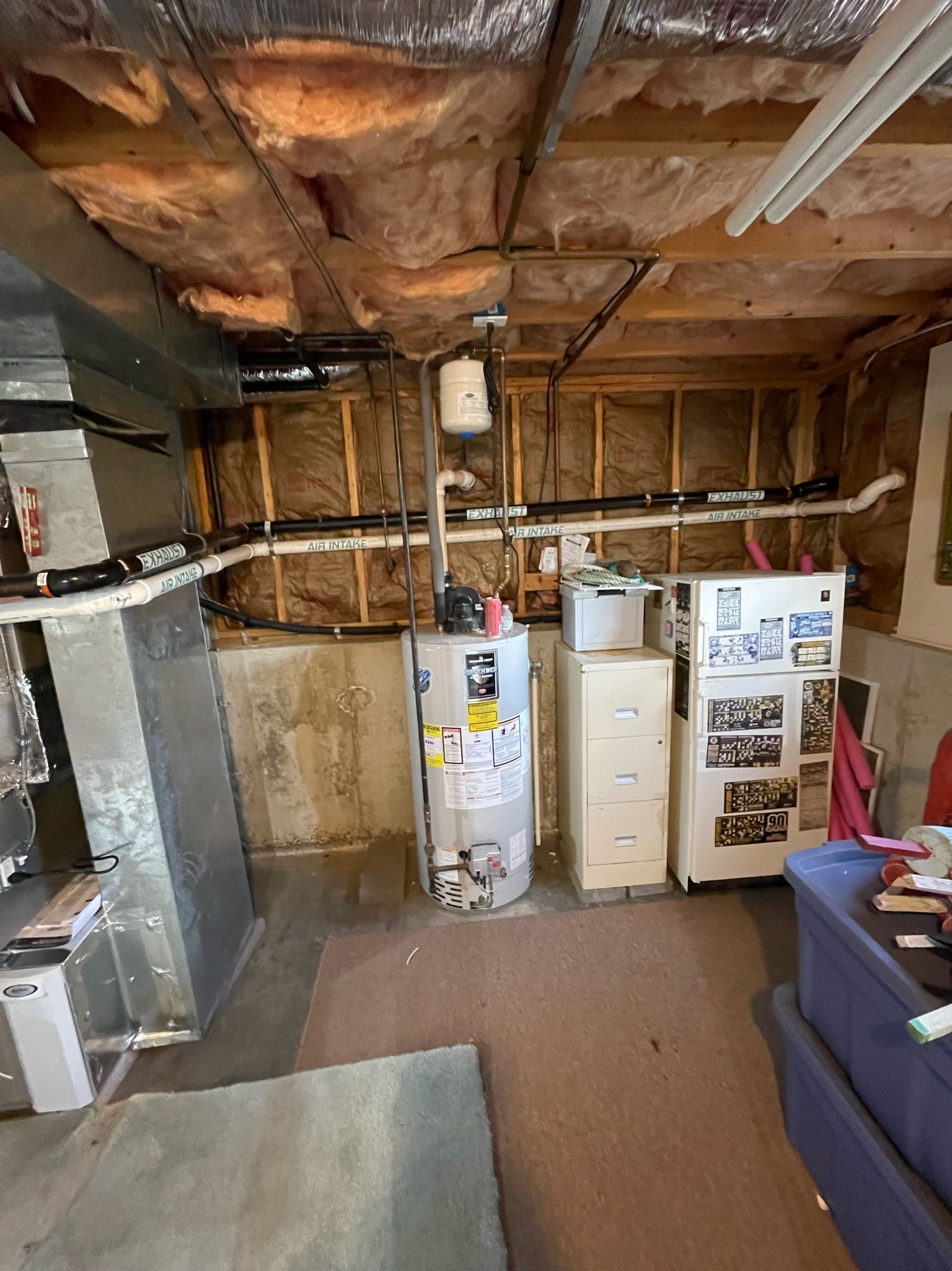 Basement with water heater, appliances, ductwork, insulation, and storage bin. Brown, beige, and gray colors.