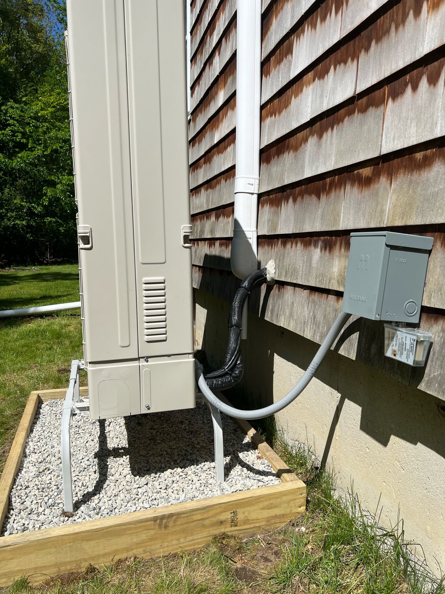 An air conditioning unit next to a house with an electrical box.