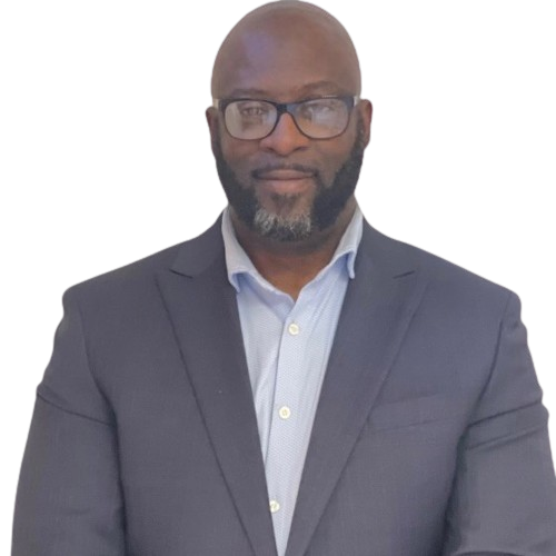 Man with a bald head, beard, and glasses in a suit and open-collared light blue shirt.