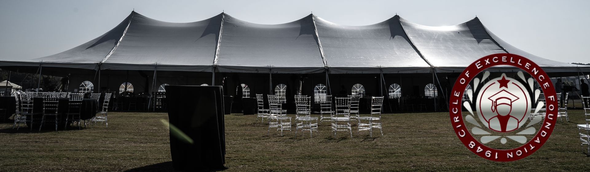 Large white tent set up on a grassy field. Red and silver logo on the right.