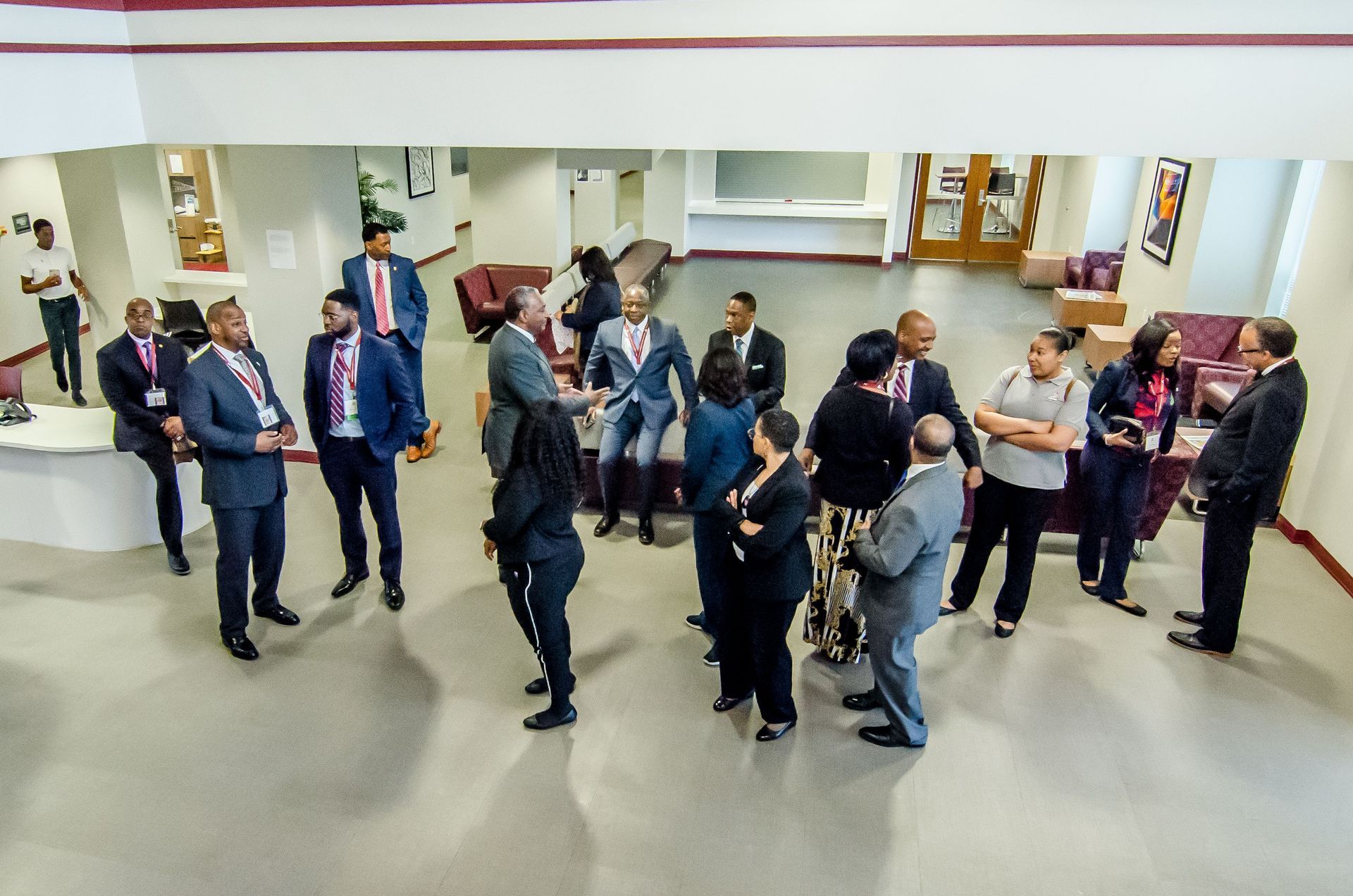 Group of people in business attire gathered in a brightly lit, open-plan space.