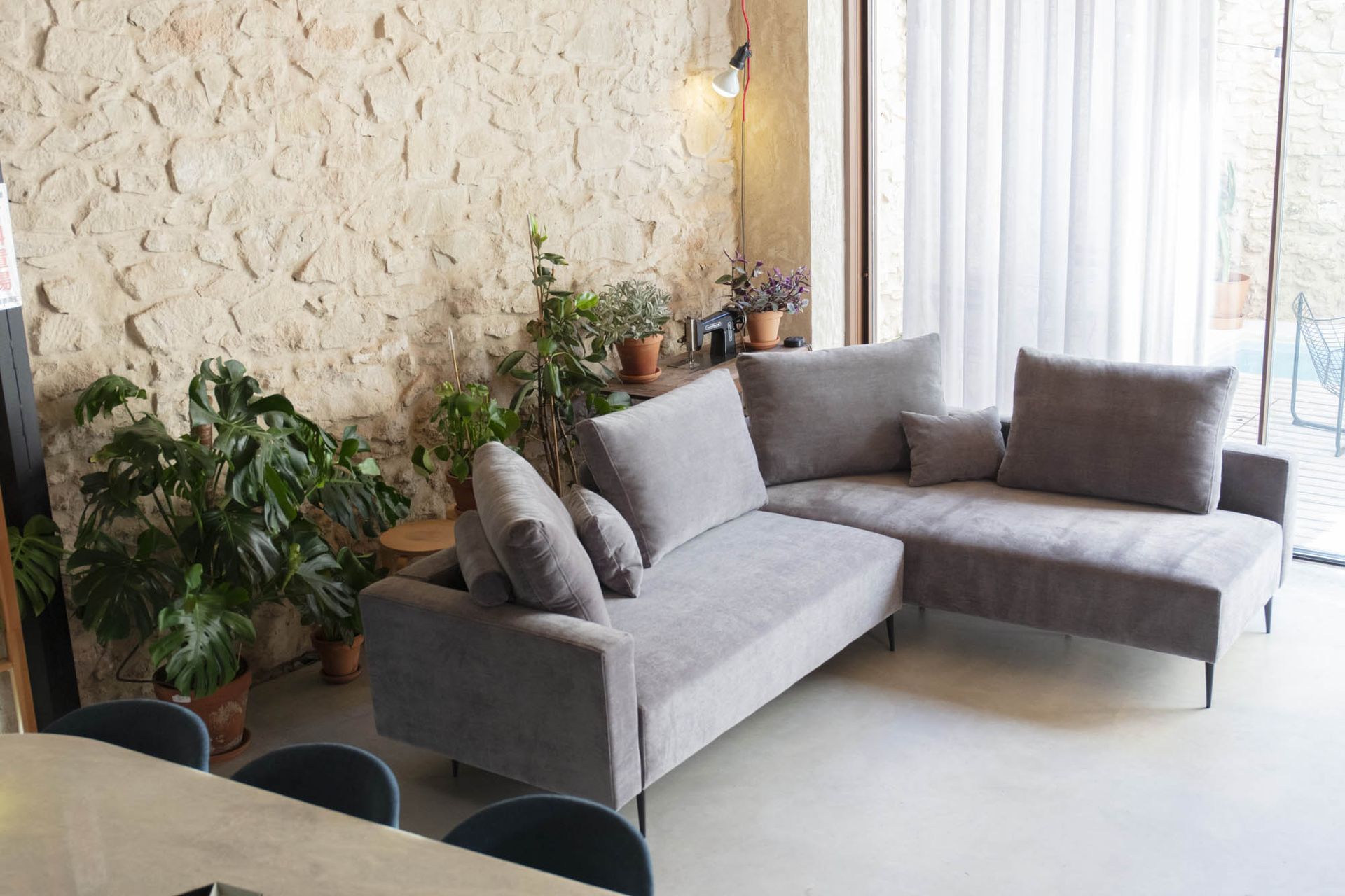 Un soggiorno con un divano Redford e delle piante di fronte a un muro di pietra.