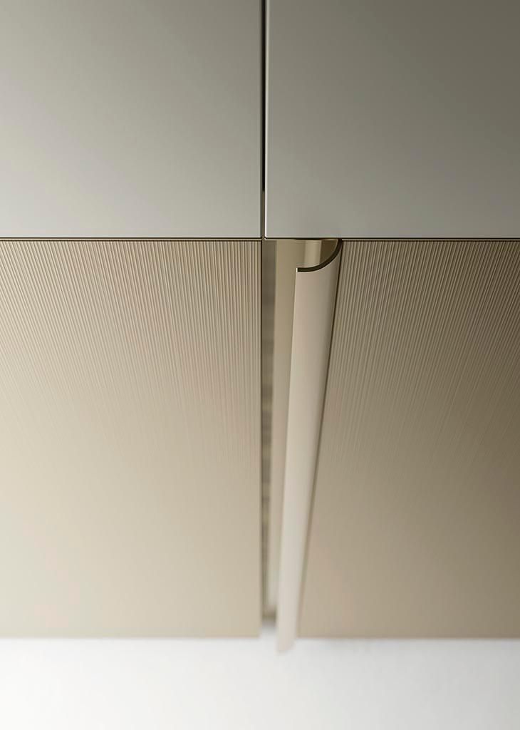 Primo piano di due ante riflettenti di un mobiletto, una delle quali leggermente socchiusa, con finitura beige chiaro.