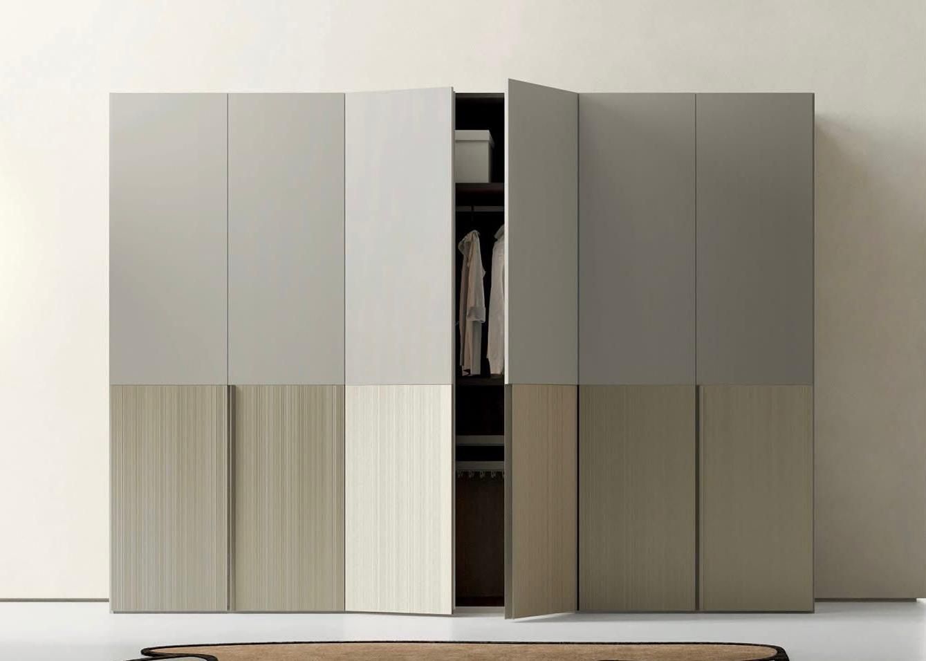 Armadio moderno con ante beige e marroni, parzialmente aperte, che lasciano intravedere i vestiti appesi.