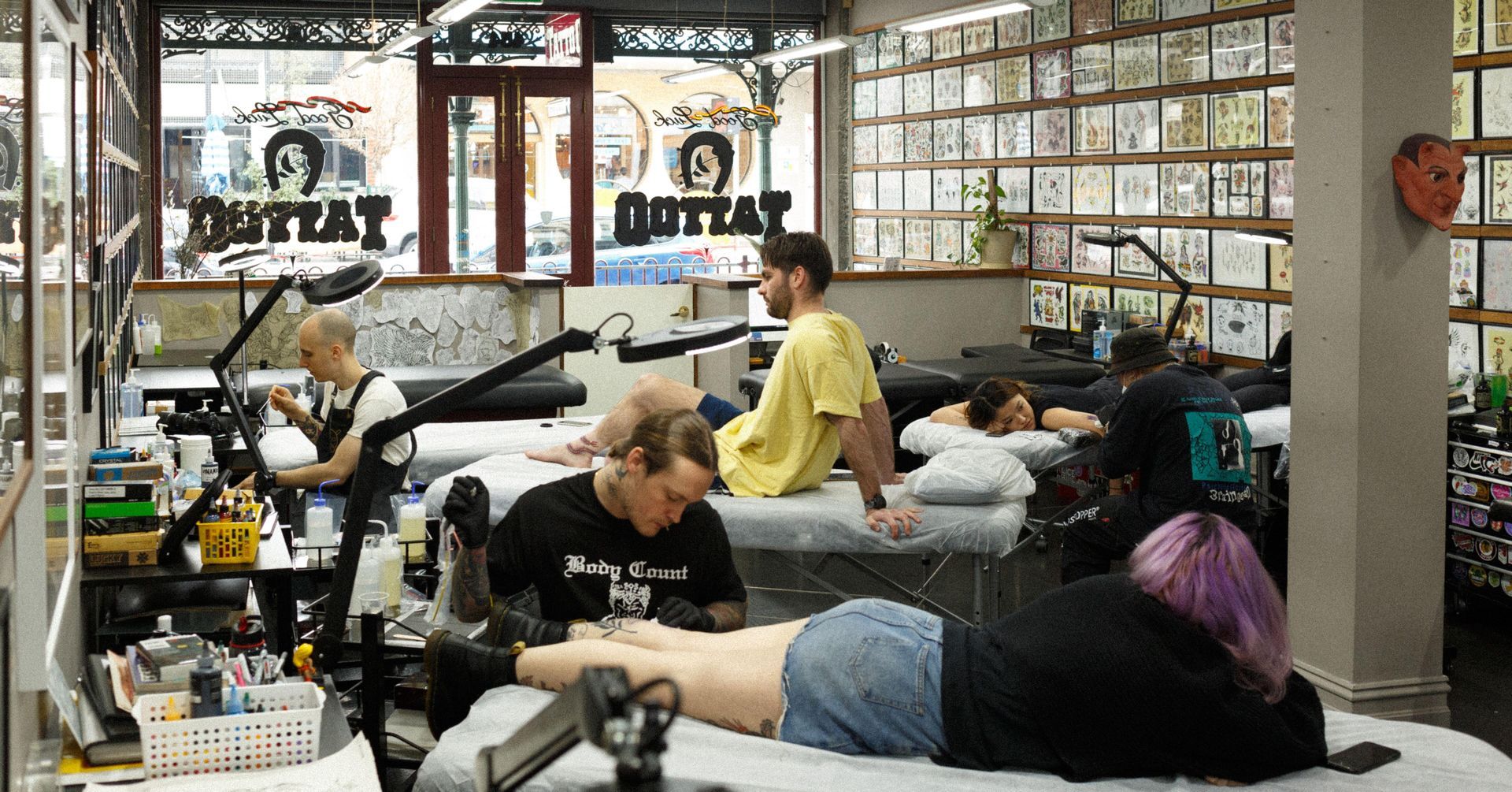 a woman is getting a tattoo on her leg in a tattoo shop .
