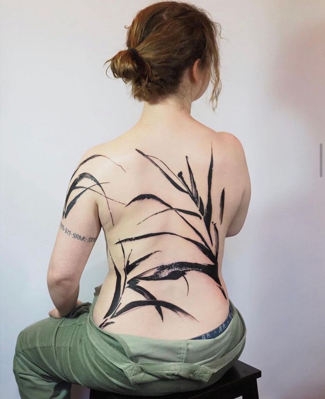 a woman has a tattoo on her back 