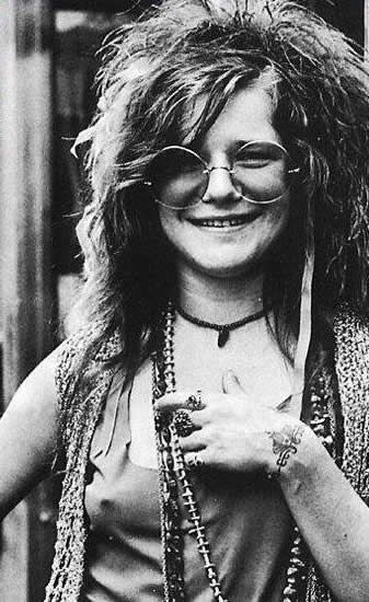 a black and white photo of a woman wearing glasses and a necklace .