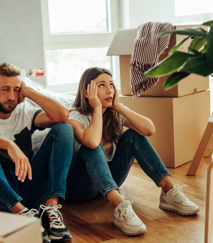 Couple sits amidst moving boxes, looking stressed and overwhelmed. Life transitions can be hard, we make them easier at Reset and Rise.