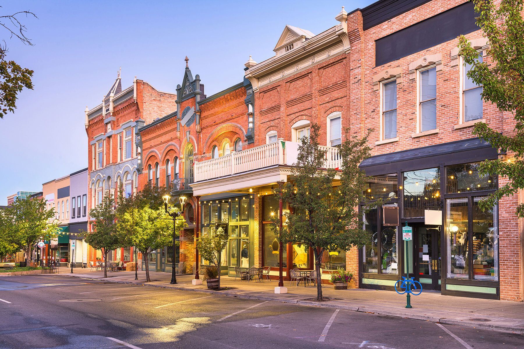 Row of brick storefronts with awnings, trees, and streetlights in the Provo downtown area.