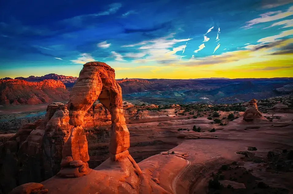 Delicate Arch at sunset in Arches National Park, Utah; orange rock formation against colorful sky. Trauma informed therapy for Utahns. 