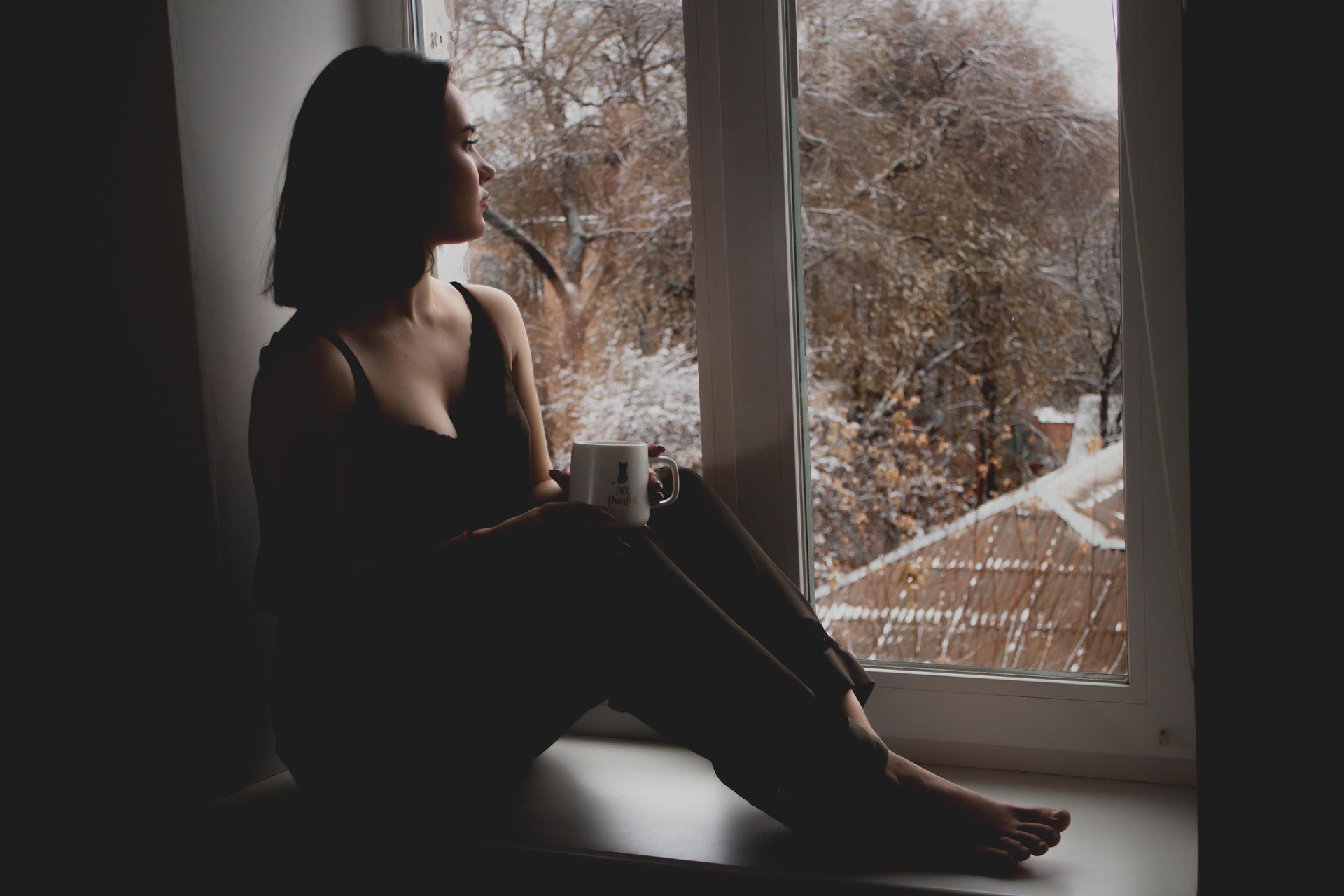 A woman sitting calmly by a sunlit window, looking relaxed and thoughtful