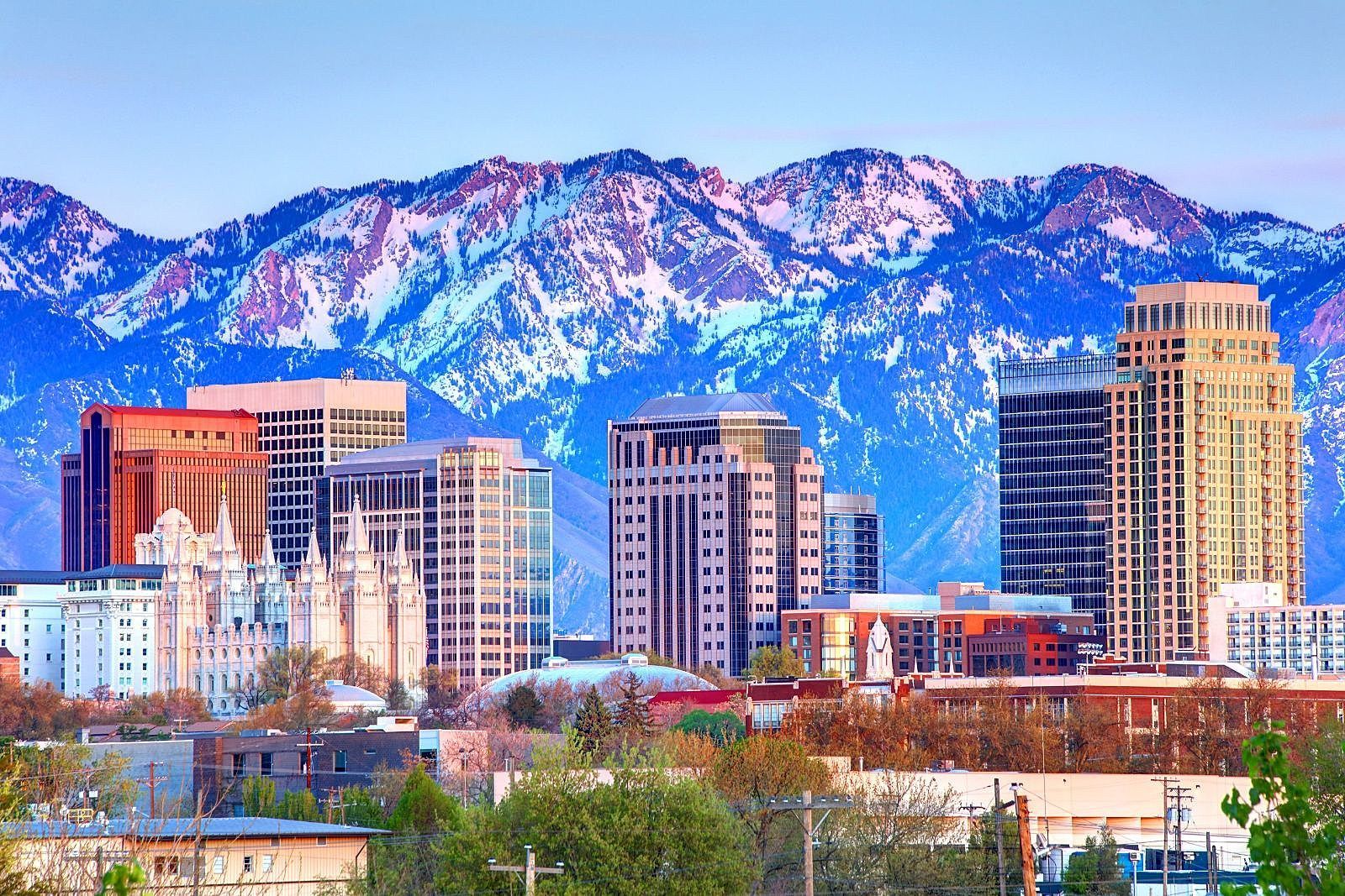 Salt Lake City skyline with mountains in background. Skyscrapers in front of snow-capped peaks. Reset and Rise Counseling can help alleviate pressure from Utah specific expectations. 