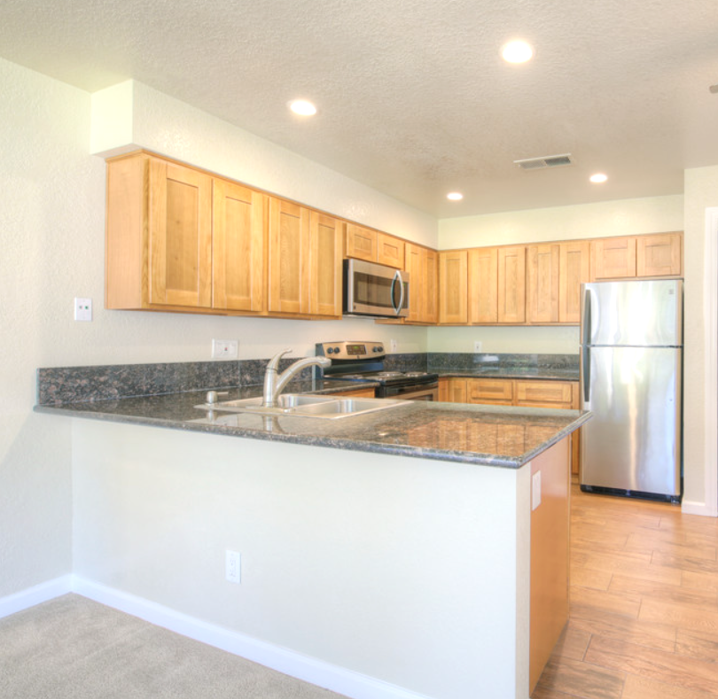 Kitchen with light wood cabinets, stainless steel appliances, and granite countertops.