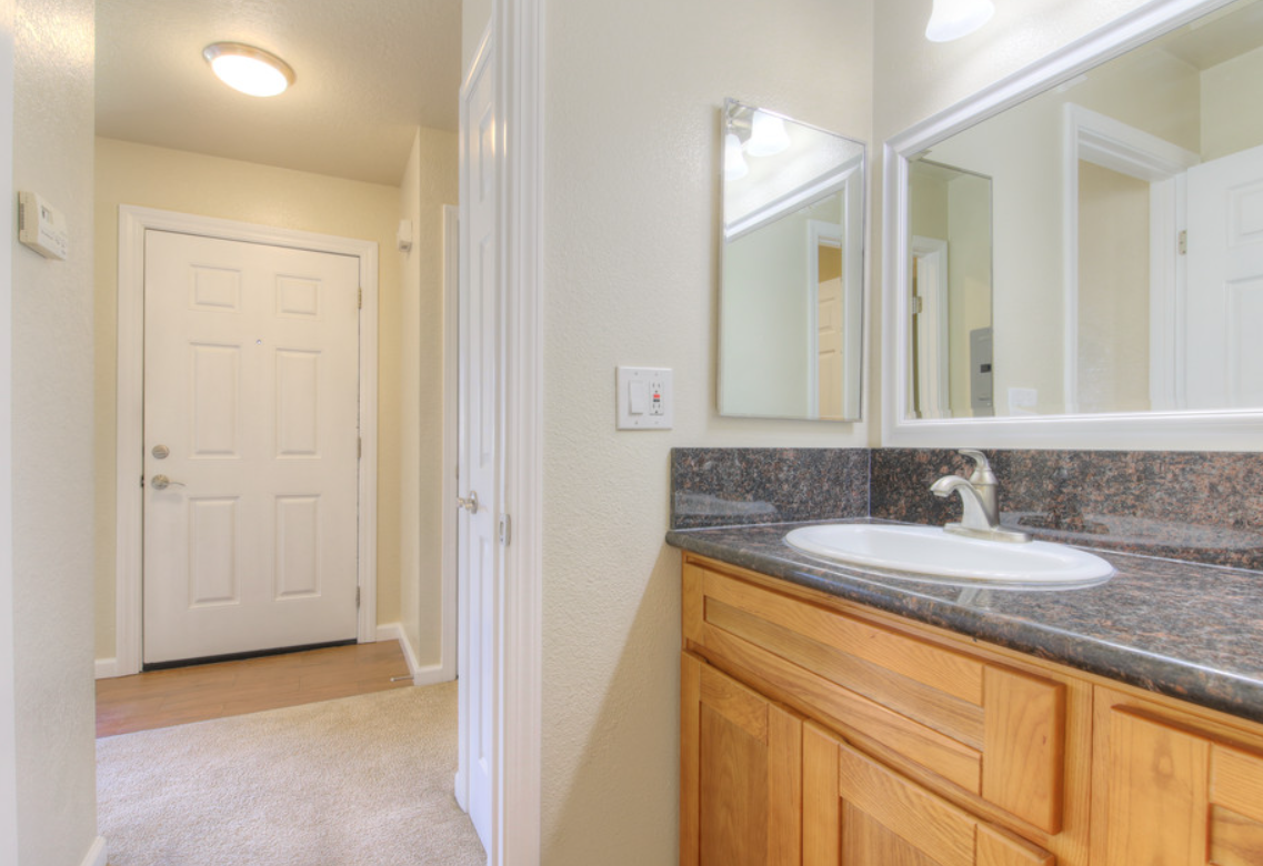 Bathroom hallway with vanity, mirror, and doorway.