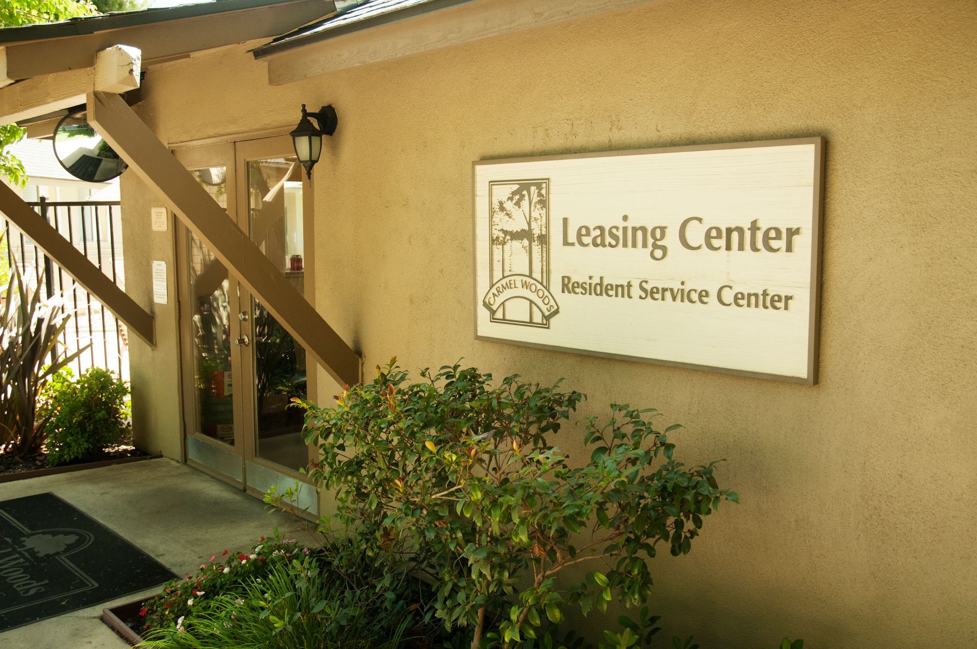 Leasing Center exterior, tan stucco building with sign, glass doors, and landscaping.
