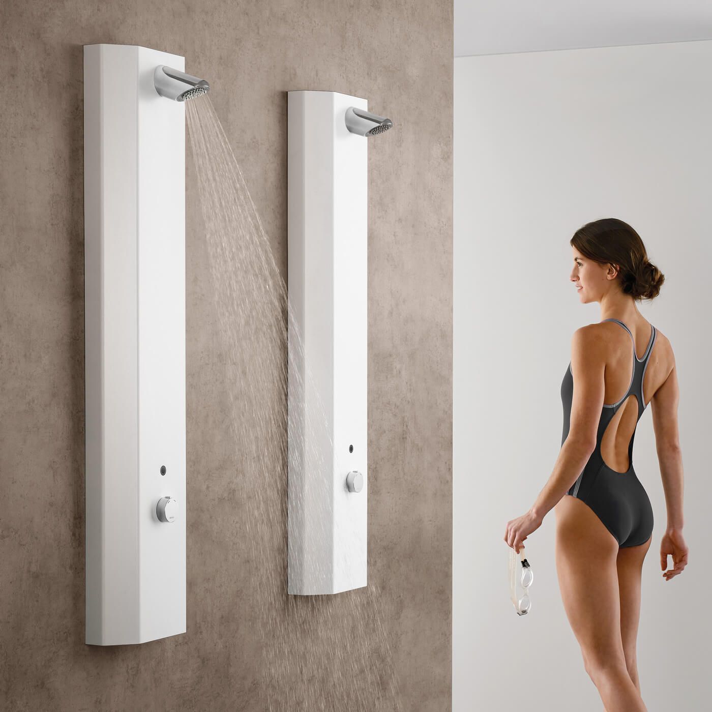 Eine Frau im schwarzen Badeanzug steht vor zwei Duschen
