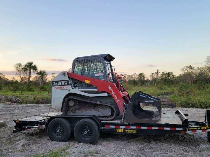 A bulldozer is sitting on top of a trailer in a field.