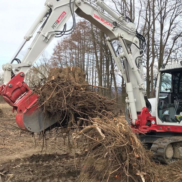 A white and red excavator is carrying a pile of roots.