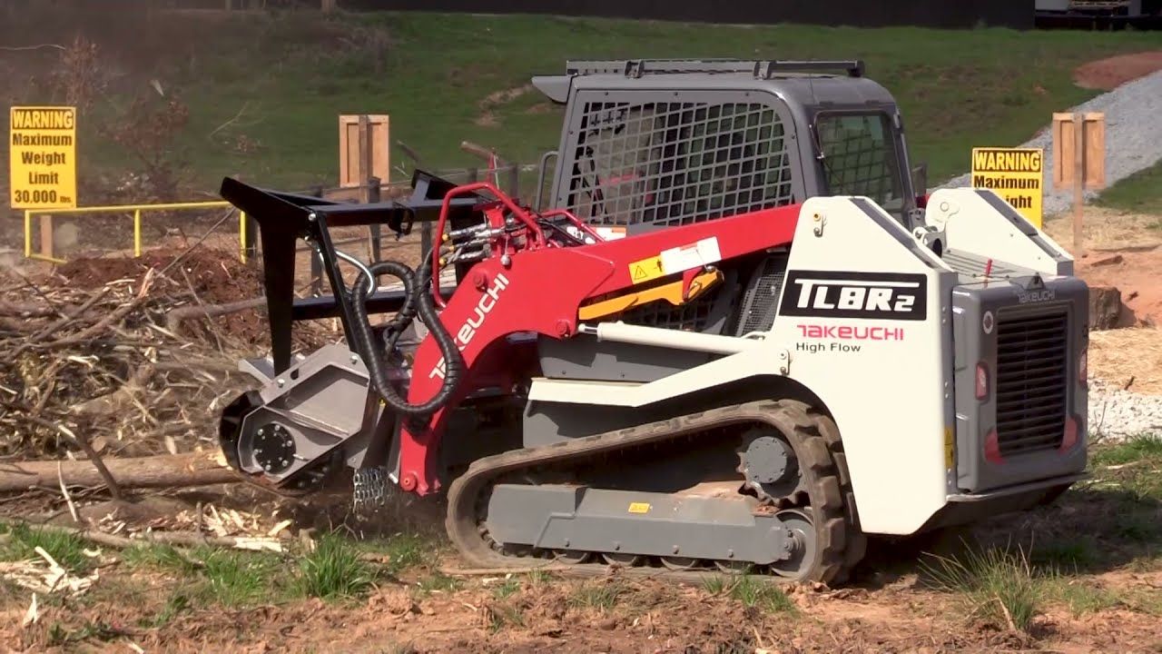 A small bulldozer is driving through a dirt field.