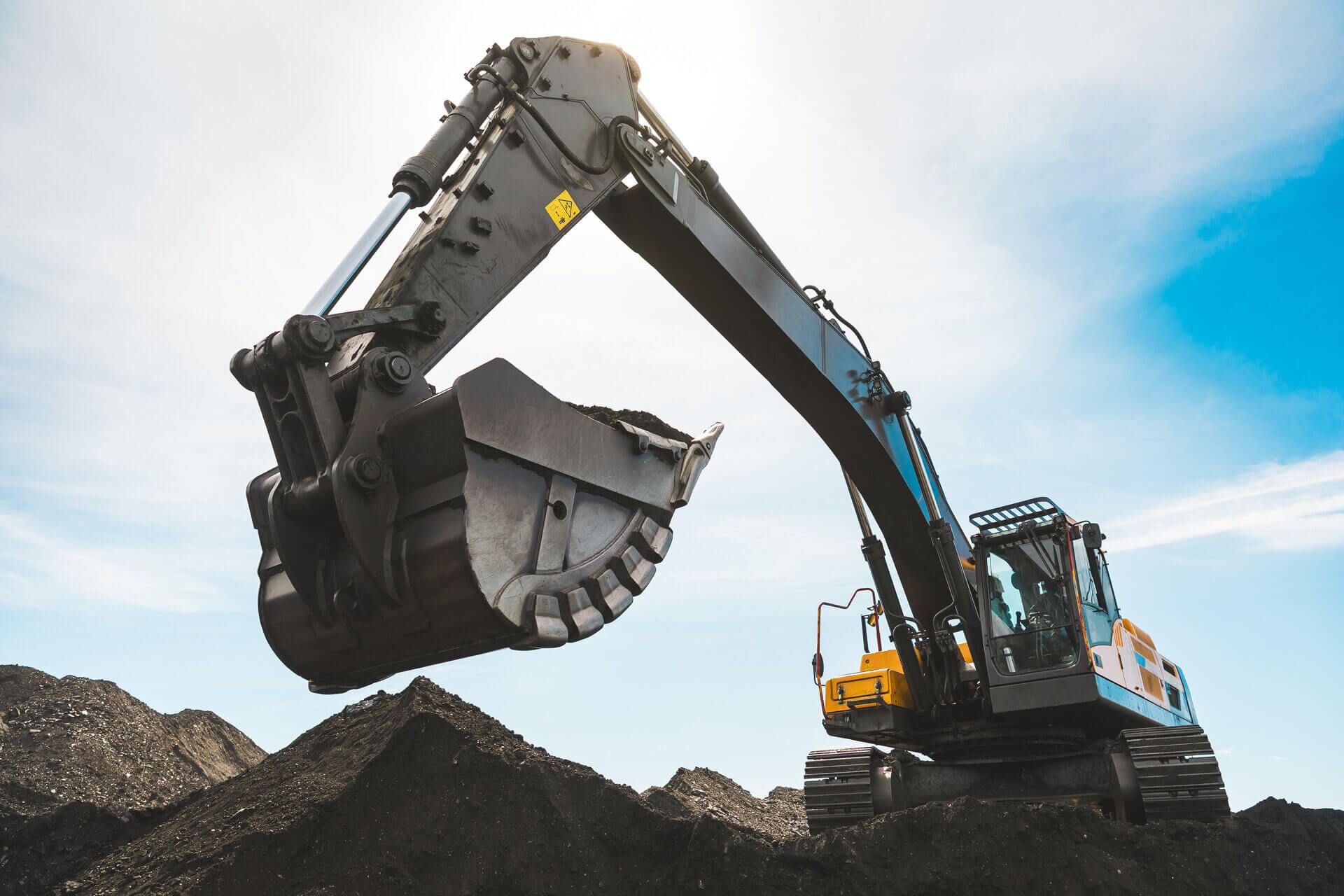 A large excavator is digging in a pile of dirt.