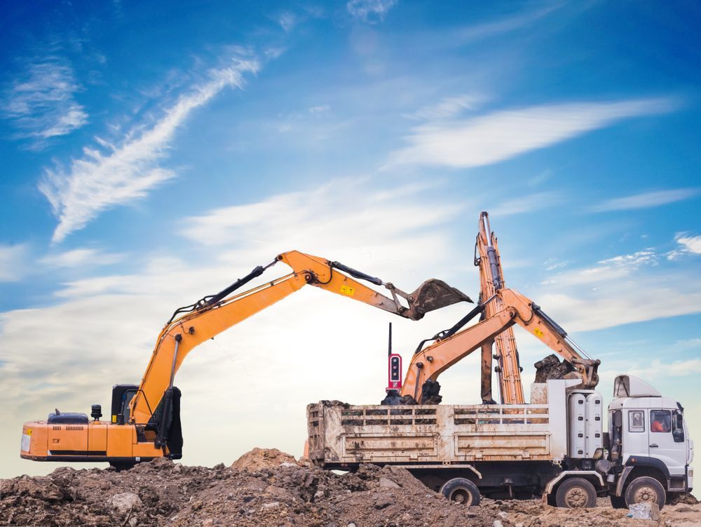 Two Yellow Excavators Loading a Dump Truck With Dirt, Blue Sky Background — Ace Clearing & Mulching In Old Bar, NSW