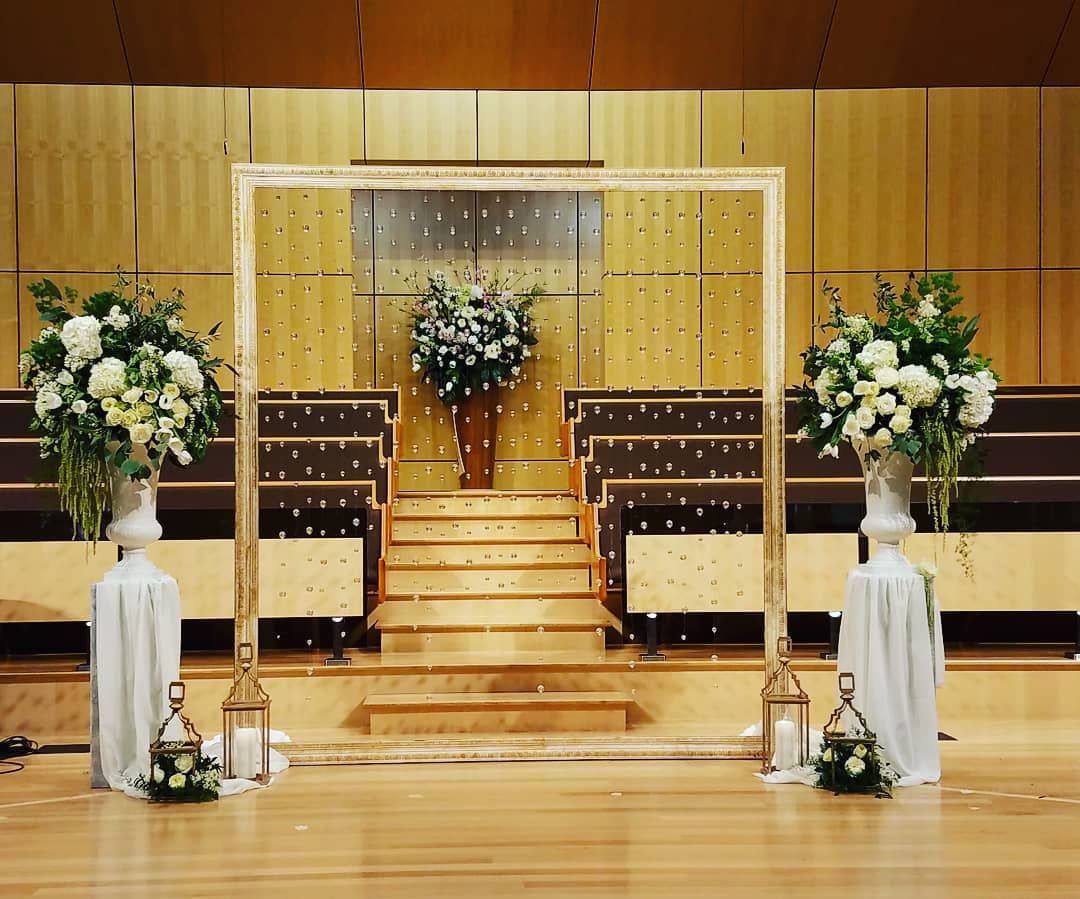 A wooden arch decorated with flowers and candles in a large room.