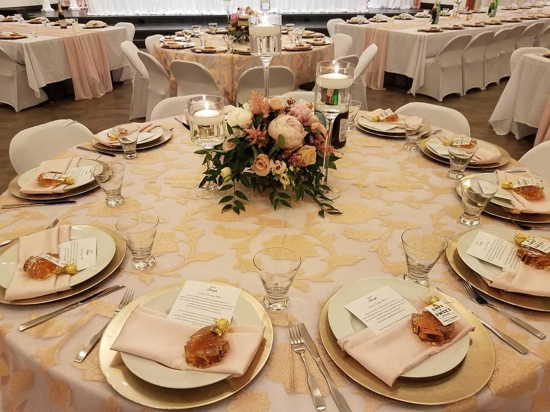 A table set for a wedding reception with plates , napkins , candles and flowers on it.