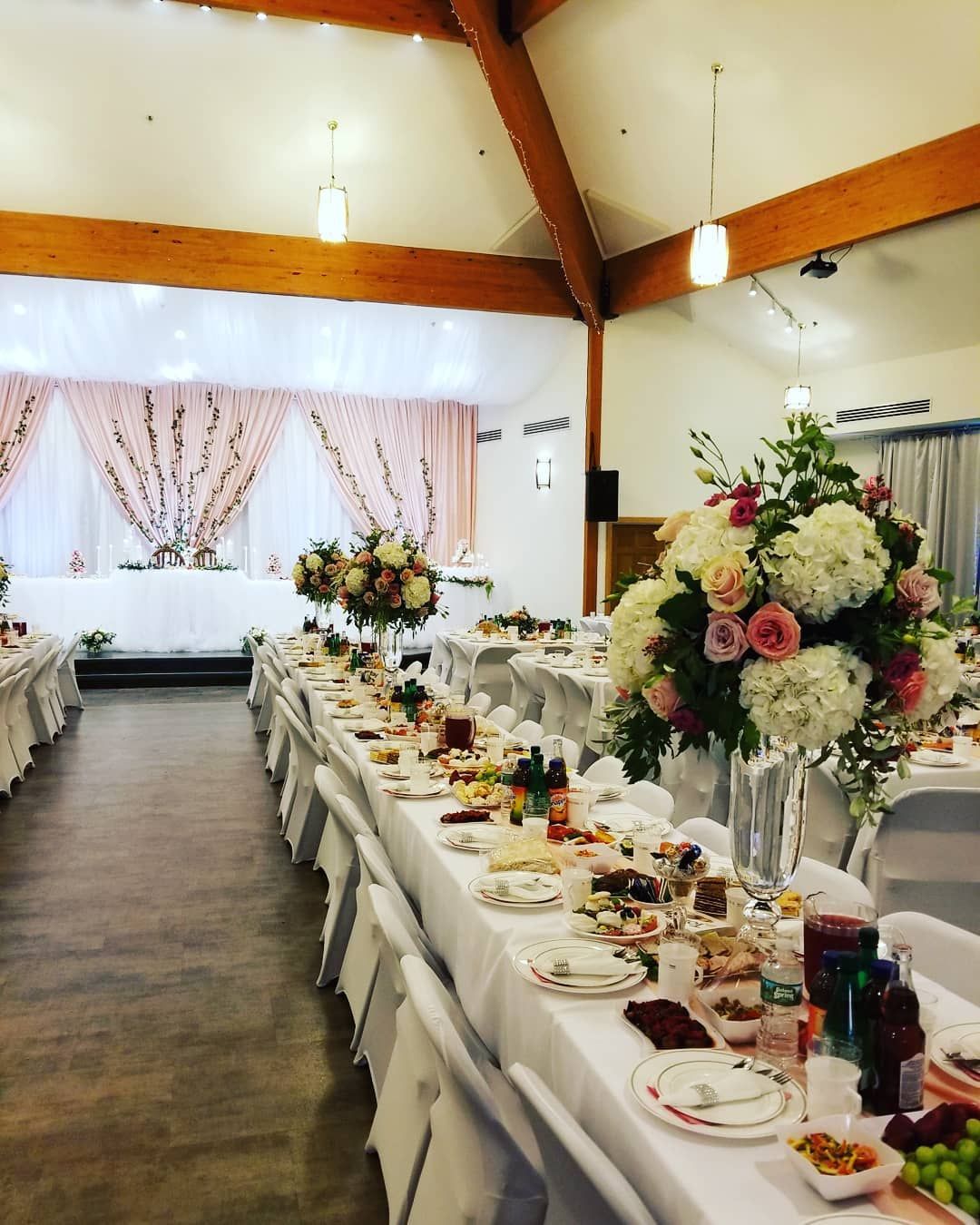 A large room with tables and chairs set up for a wedding reception.