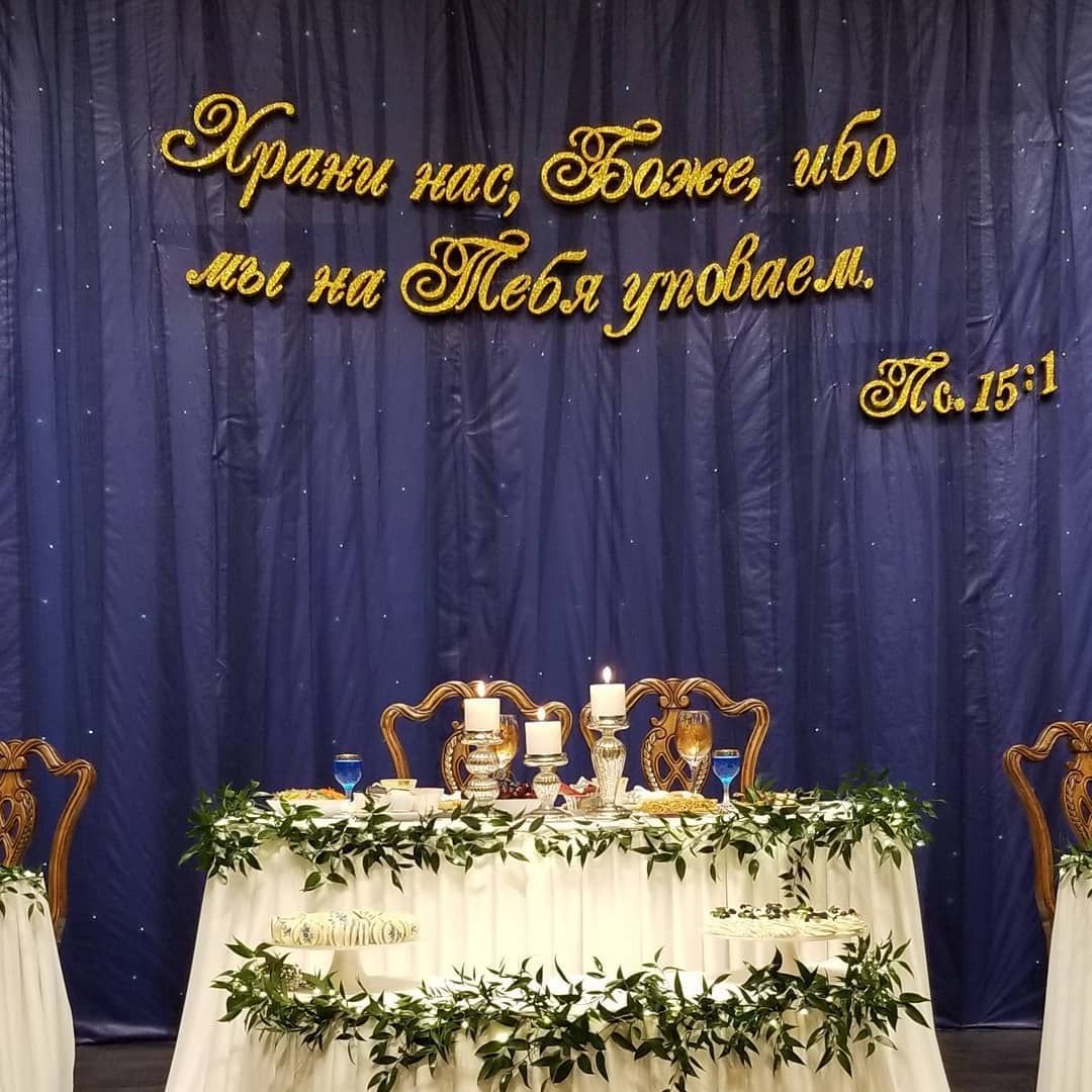 A table with flowers and candles in front of a blue curtain