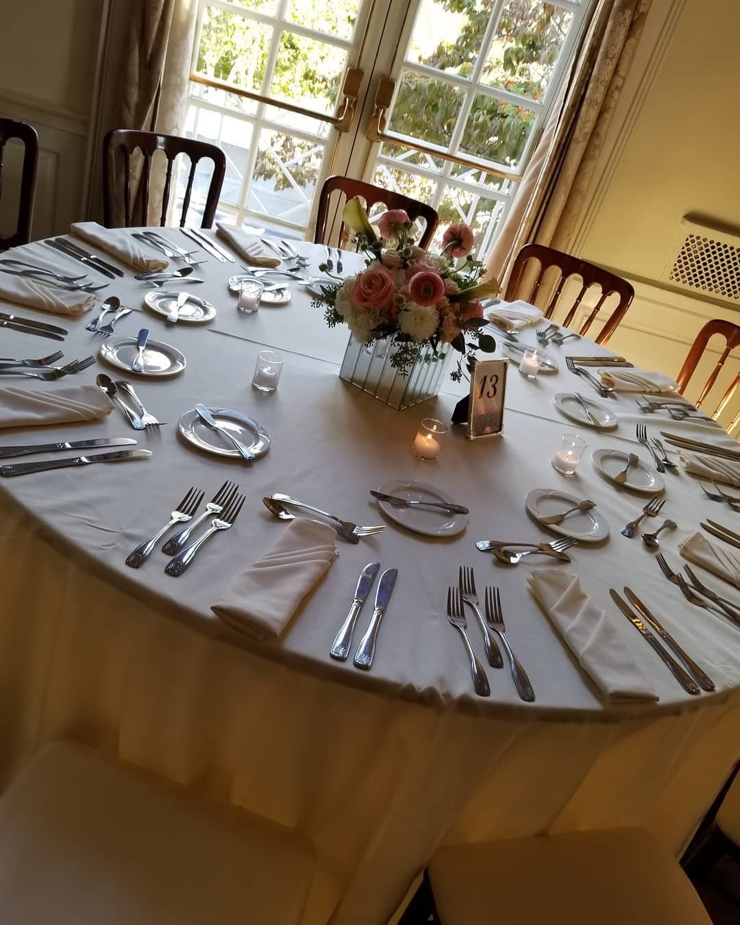 A round table with silverware and a vase of flowers on it
