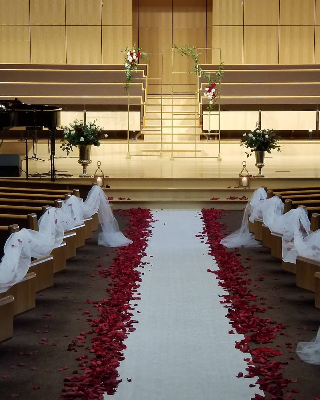 A church with a white aisle lined with red rose petals