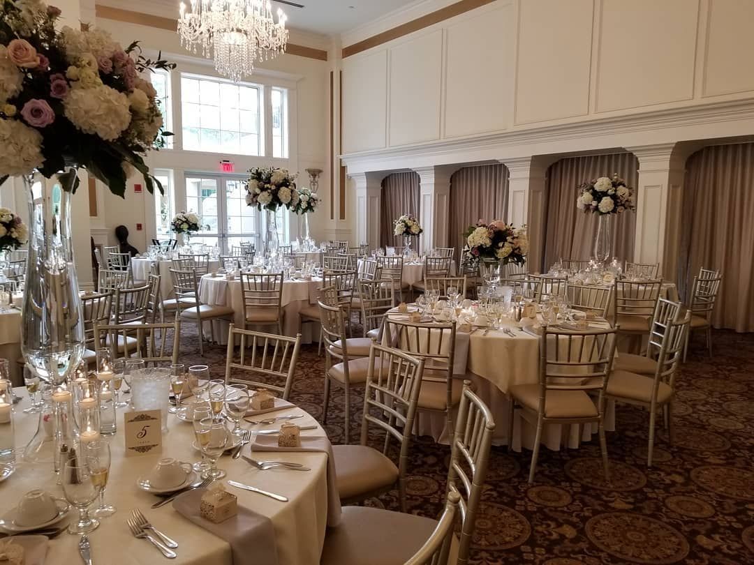 A large room with tables and chairs set up for a wedding reception.