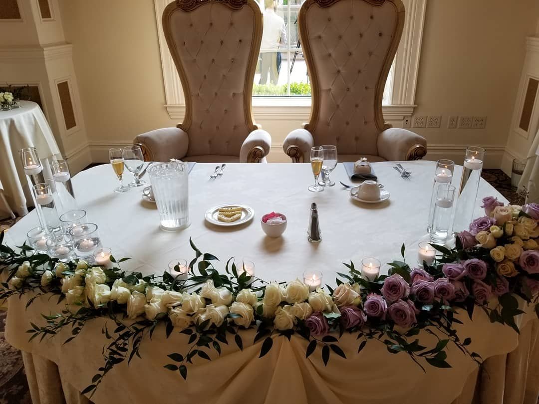 A couple of chairs are sitting at a table with flowers and candles.