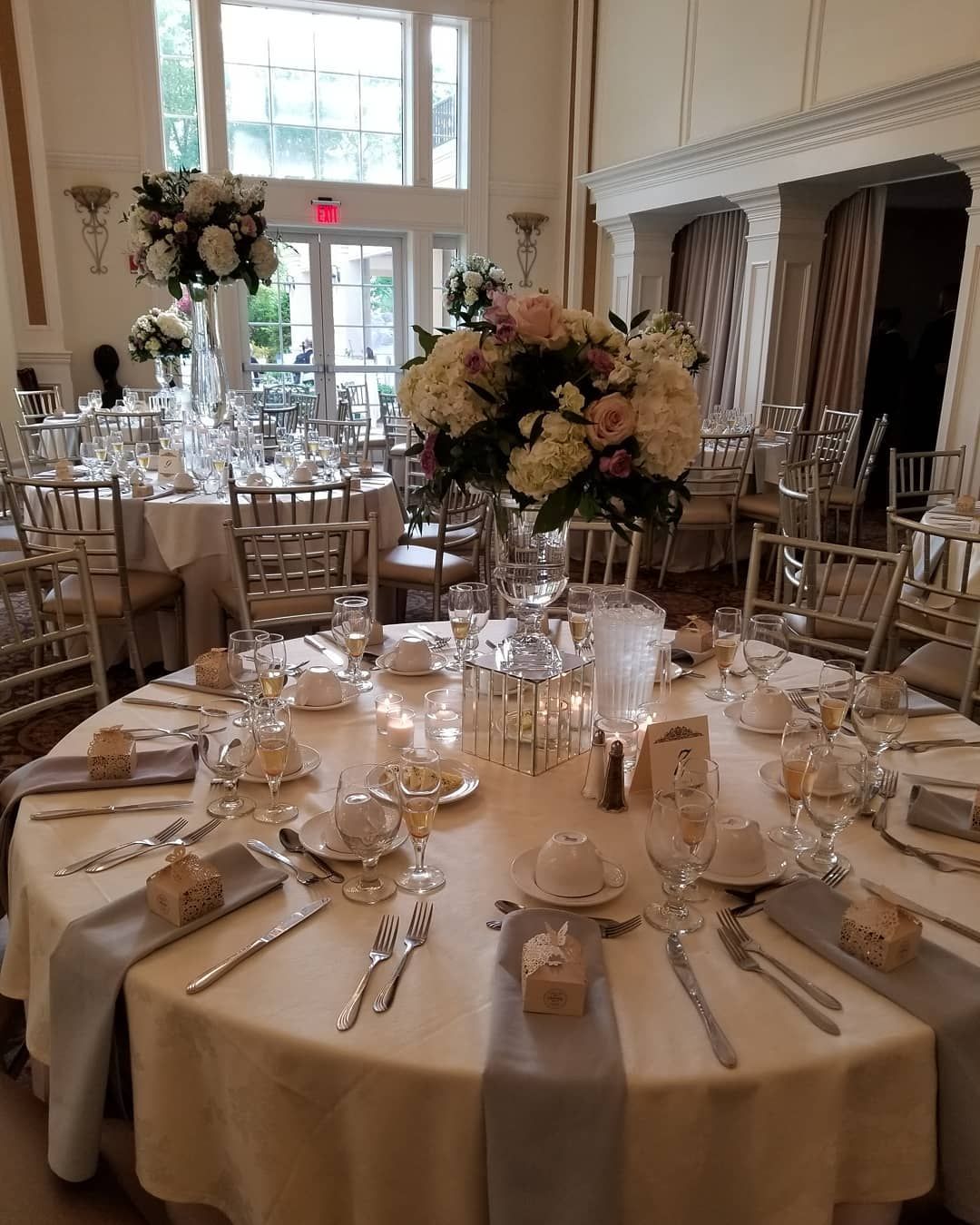 A table set for a wedding reception with a vase of flowers on it.