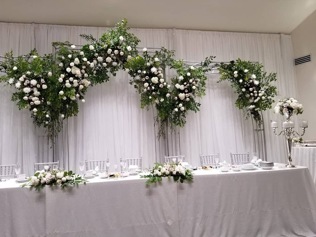 A long table with flowers on it in front of a white curtain.