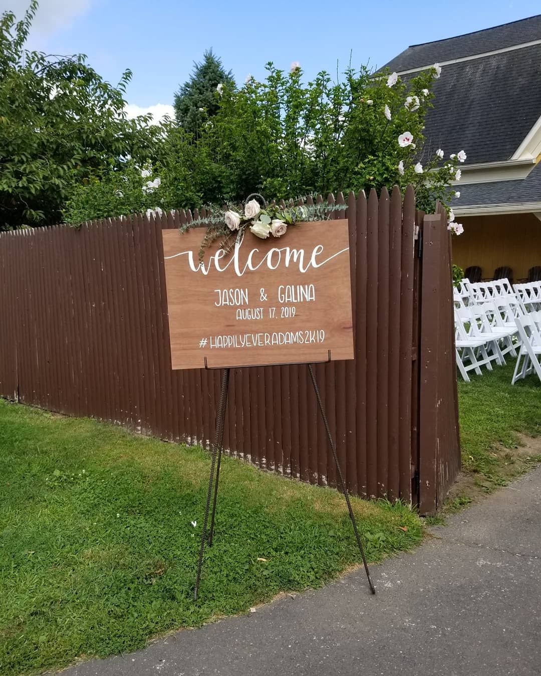 A welcome sign is hanging on a wooden fence.