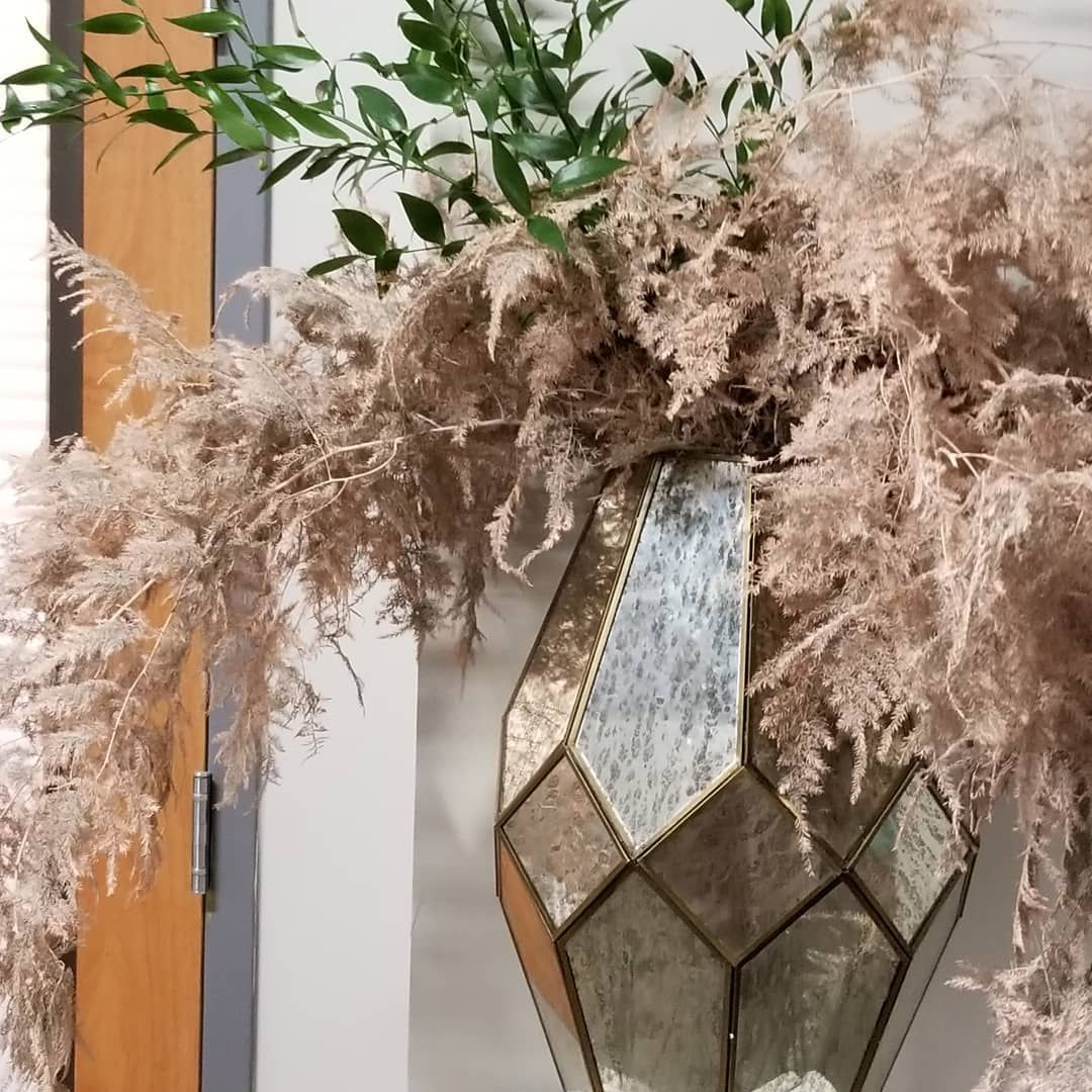 A stained glass vase filled with dried flowers and leaves