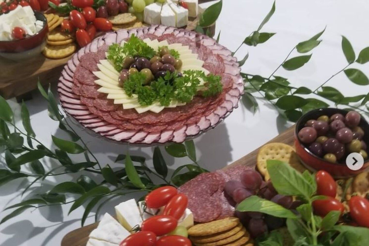 A table topped with a variety of food including cheese , crackers , tomatoes and olives.