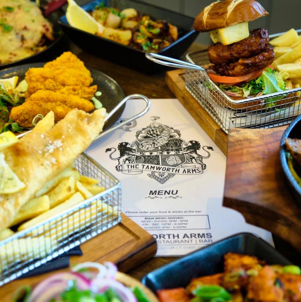 Table of pub food including a burger, fish and chips, and menu.