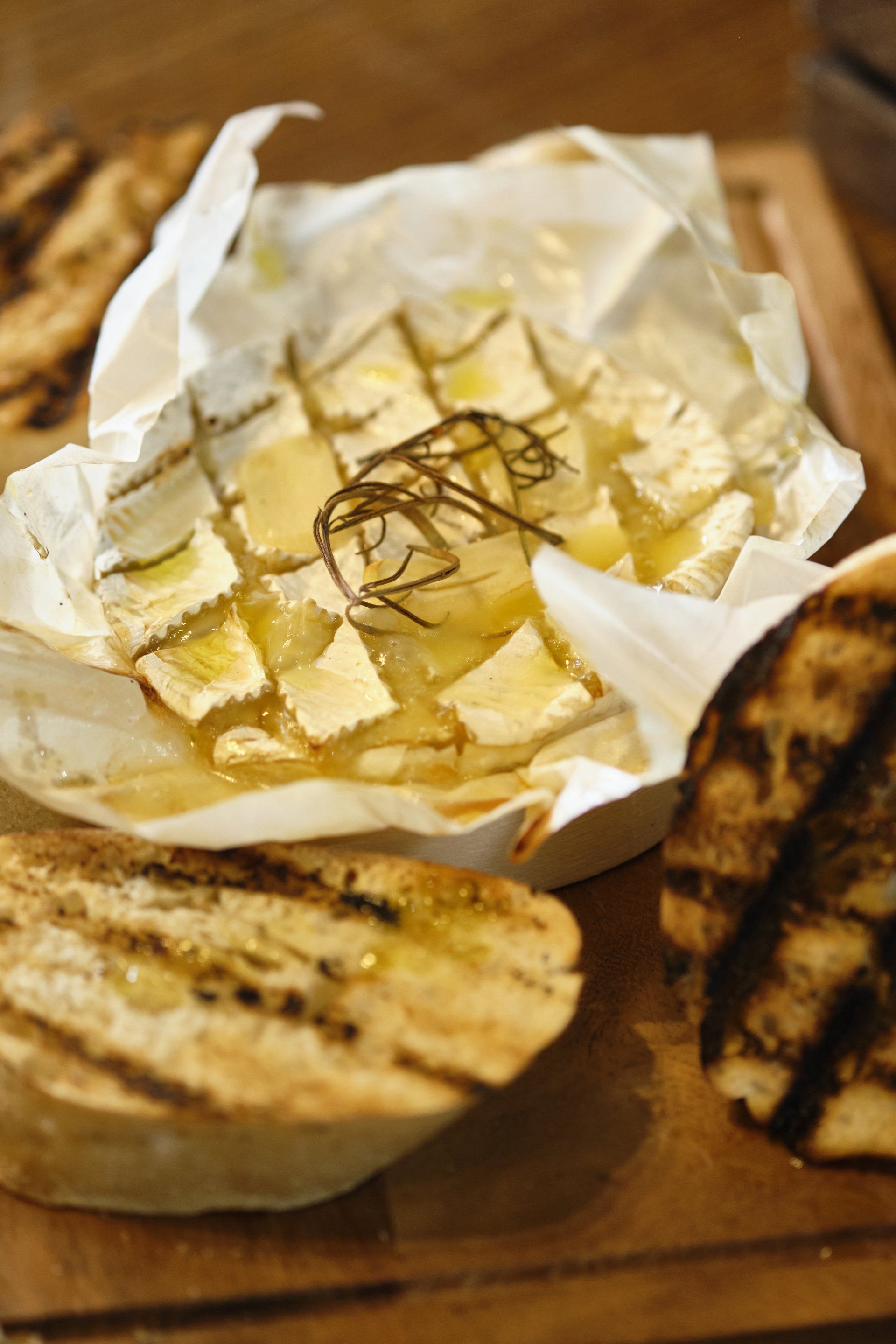 Baked brie with olive oil and rosemary, served with grilled bread.