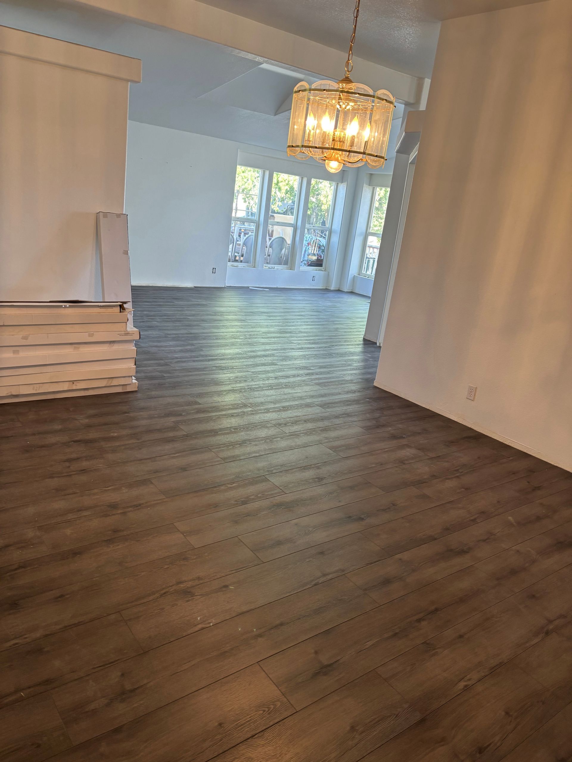 Newly installed wood-look flooring in a bright interior. A chandelier hangs from the ceiling.
