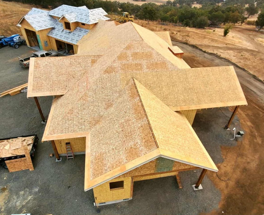New house under construction with exposed wooden roof and walls.