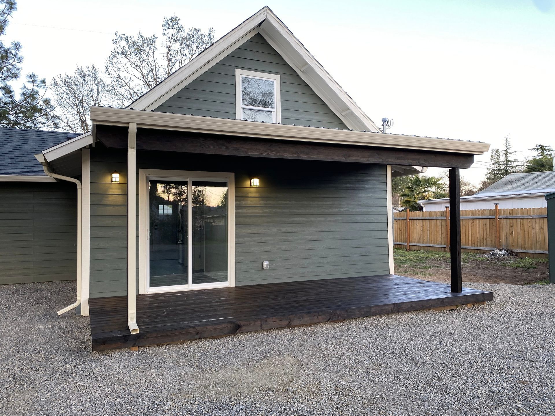 A green house with a patio has dark flooring and a sliding glass door.