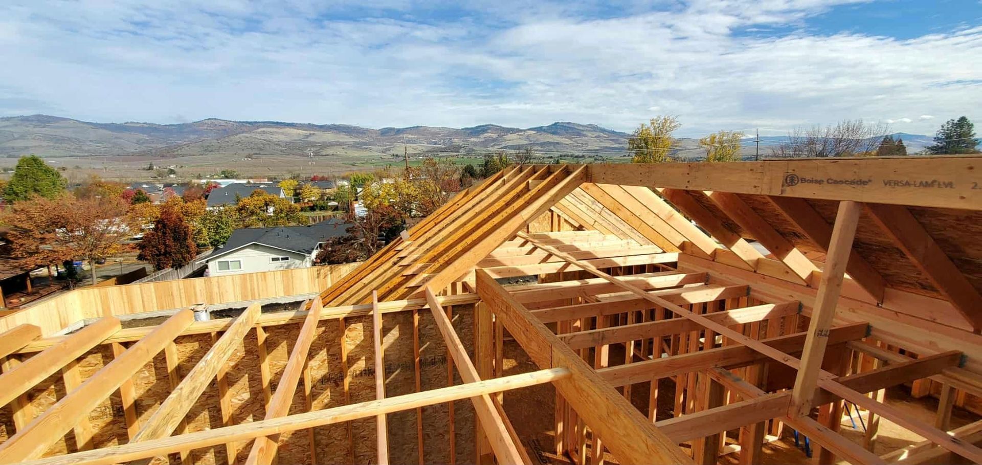 Construction of a wooden house roof.  Sky and distant mountains in background.